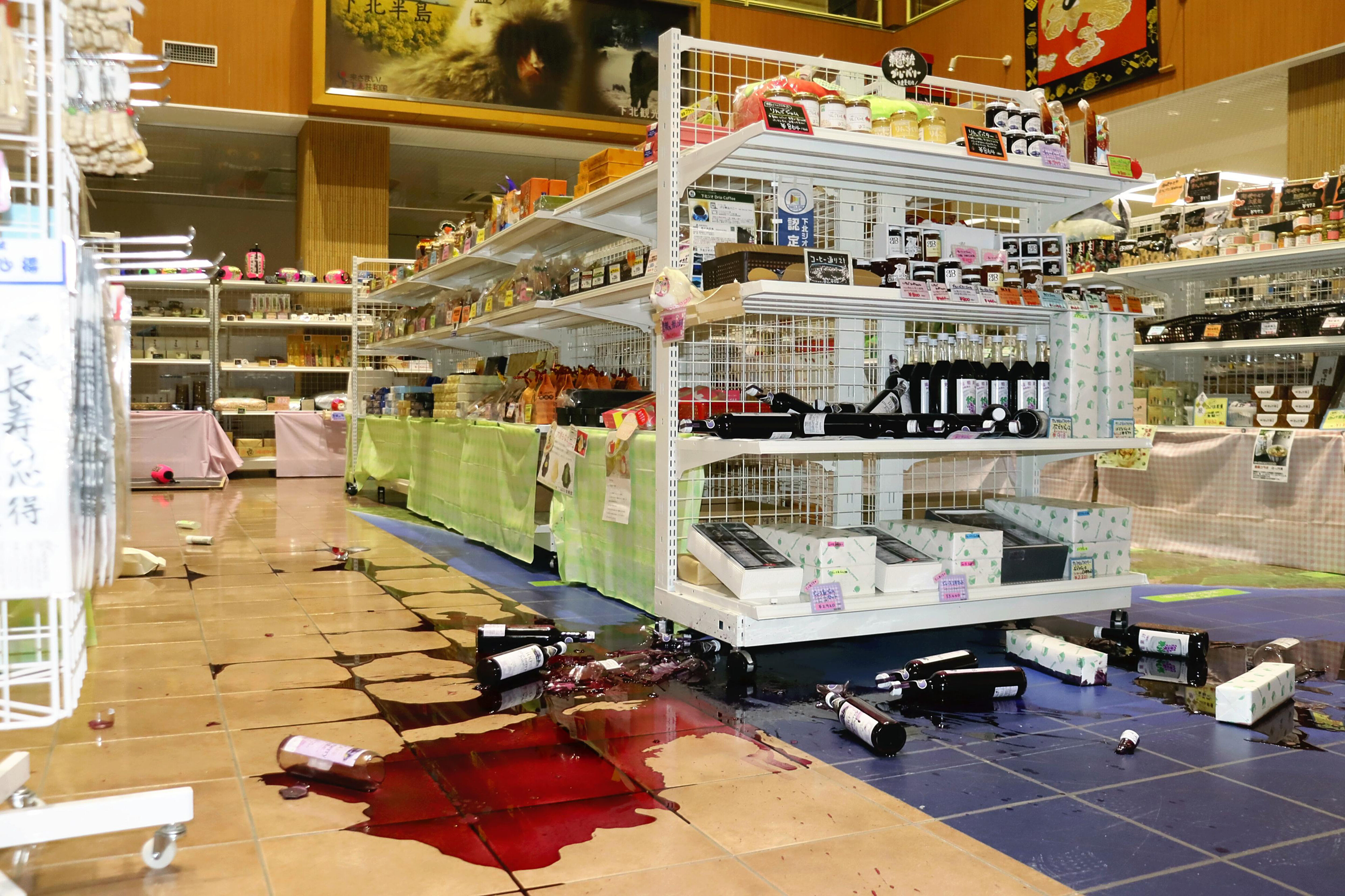 ▲▼日本青森縣陸奧市某紀念商品店，強震導致酒類等商品從貨架上翻倒。（圖／達志影像／美聯社）